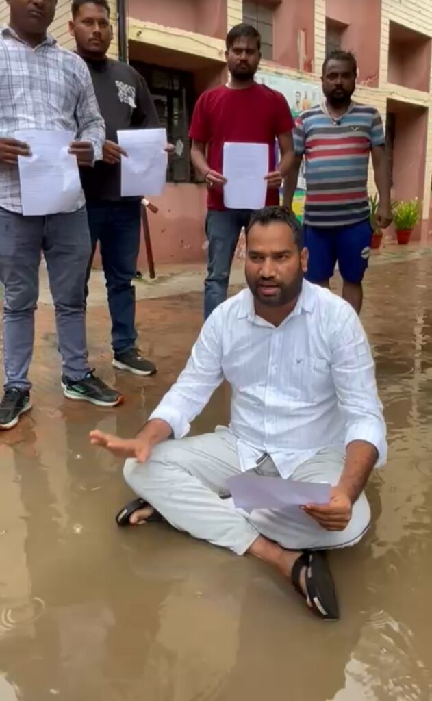 मेरठ में हड़कंप! छात्र नेता का अनोखा विरोध – बारिश के पानी और कीचड़ में बैठकर तोड़ी शिक्षा विभाग की कुंभकरणीय नींद